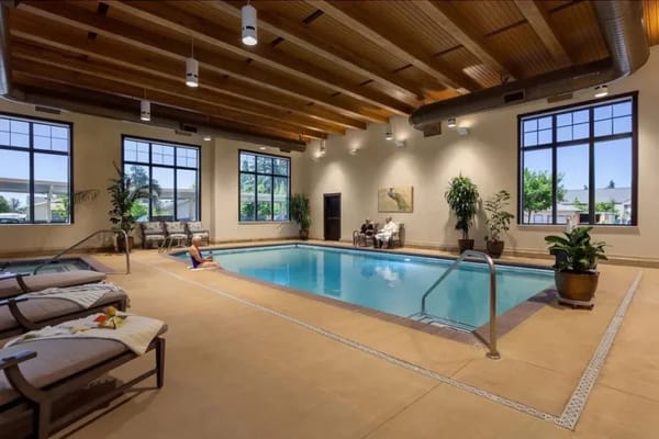 Indoor pool area with lounge chairs and plants