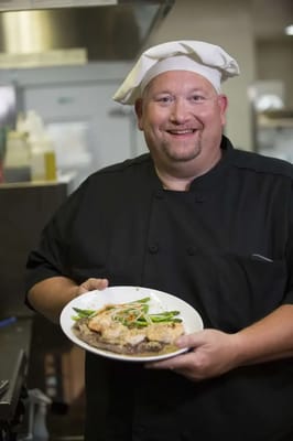Chef presenting a beautifully plated dish in the kitchen