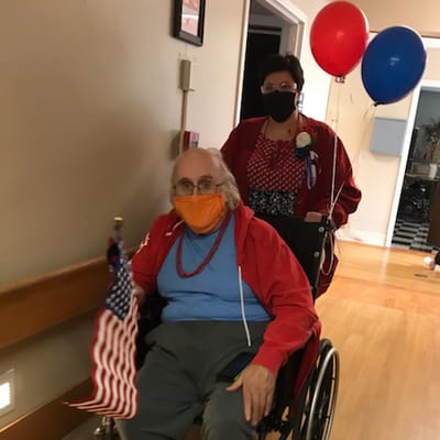 Resident in wheelchair celebrating with balloons and flag