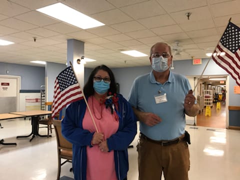 Residents holding American flags in a facility hallway