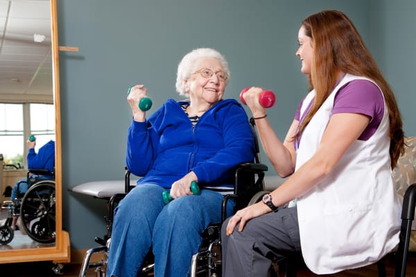 Resident exercising with staff support in an activity room