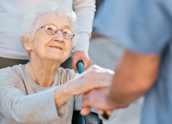 Elderly woman smiling while holding hands with a caregiver