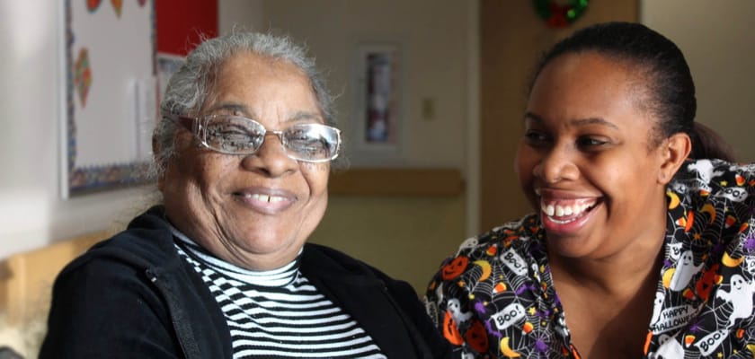 A resident and staff member smiling together in an interior space
