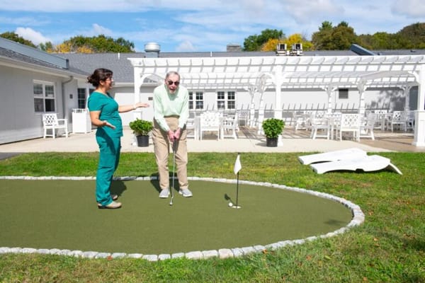 Resident practicing putting with staff in an outdoor area