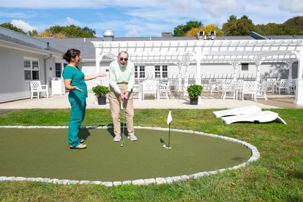 Resident practicing putting with staff in an outdoor area