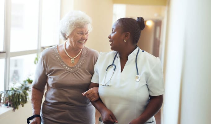 A staff member and a resident smiling together in a corridor