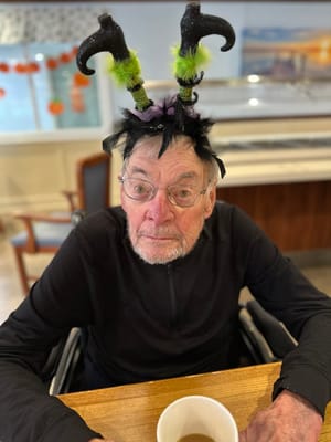 Resident wearing a festive hat in a dining area