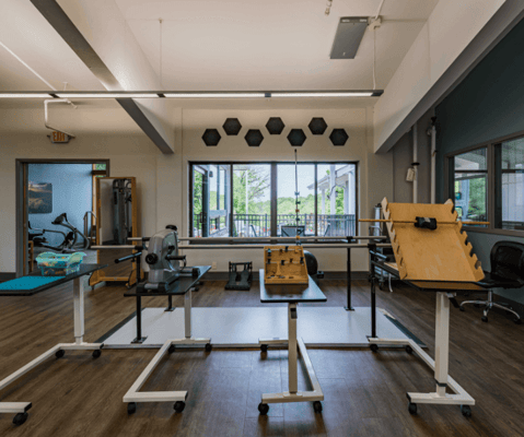 Bright exercise room with rehabilitation equipment and large windows