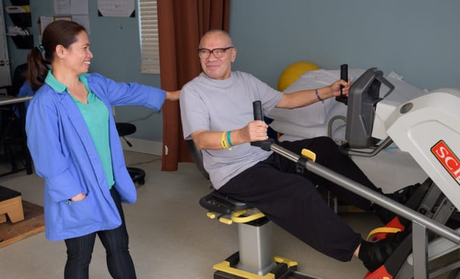 Resident using exercise equipment with staff assistance