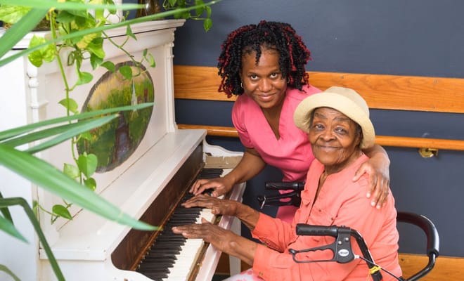 A staff member and resident playing the piano together