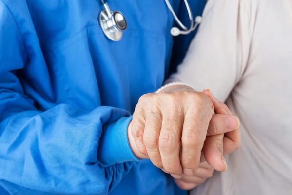 Close-up of caregiver and resident holding hands