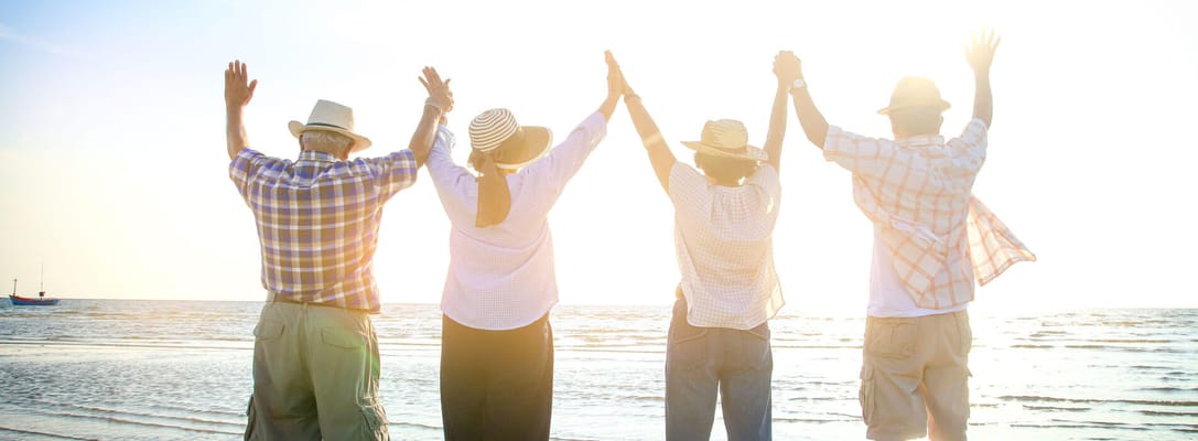 Seniors enjoying a day at the beach, hands raised