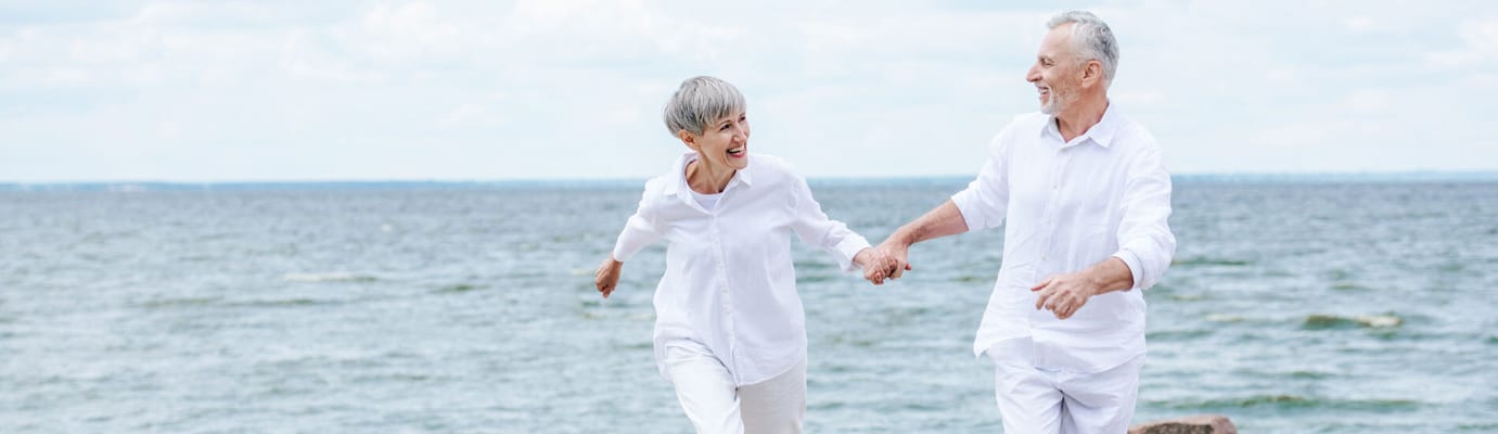 An older couple walking hand in hand by the water