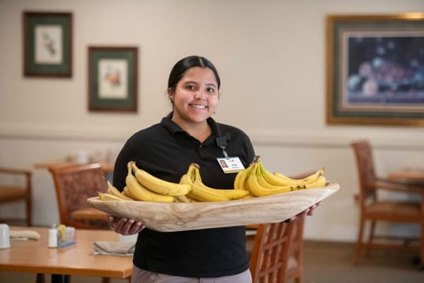 Staff member presenting a basket of bananas in the dining area