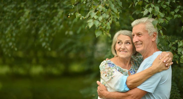 Elderly couple happily embracing outdoors