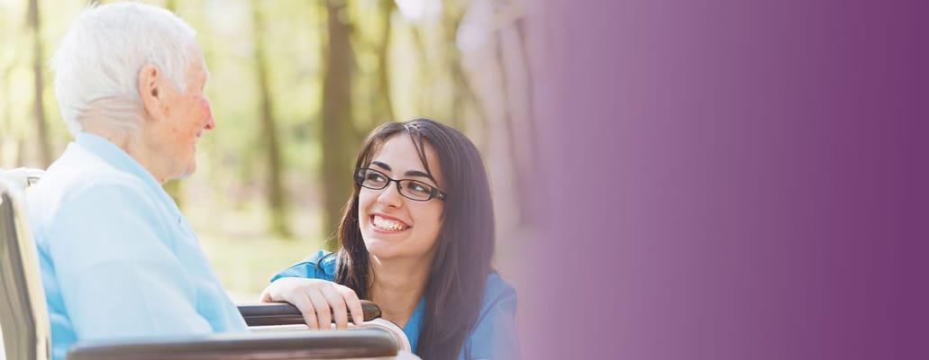 Staff member interacting with a smiling resident outdoors