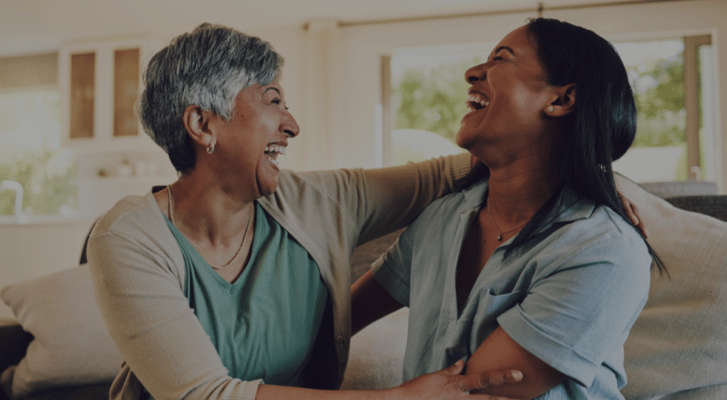 Two women joyfully laughing together in a common area