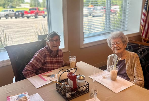 Two senior residents enjoying beverages at a table