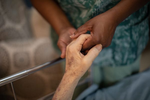 Caregiver holding a resident's hand in comforting gesture