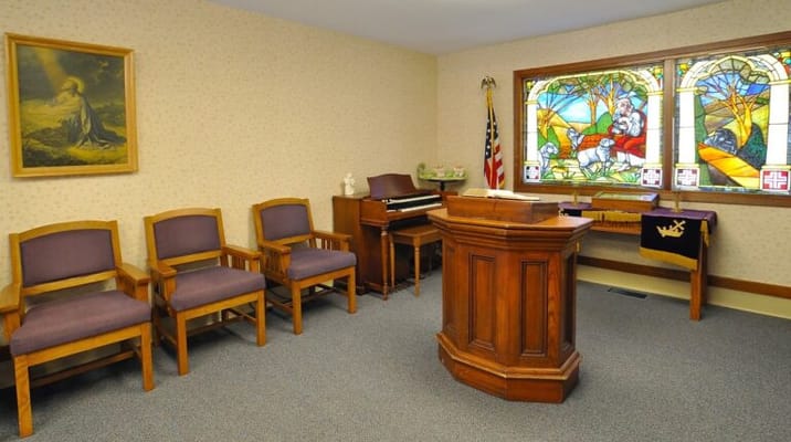 Interior chapel space with wooden furniture and stained glass window