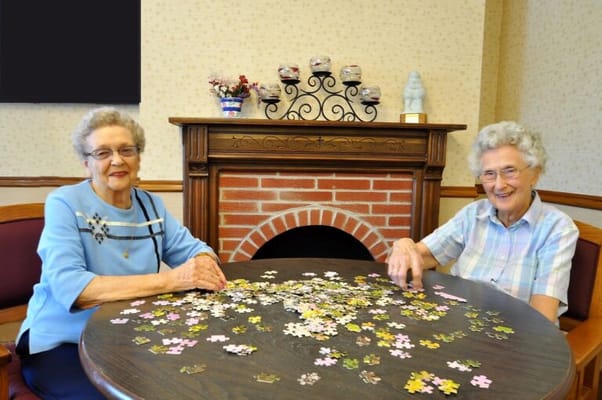 Two women working on a jigsaw puzzle in a common area
