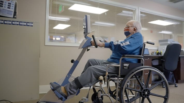 Resident exercising with therapy equipment in a common area