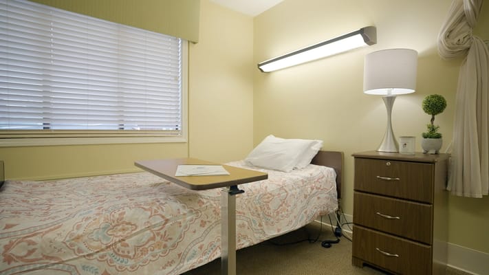 Interior view of a resident's room with a bed and nightstand