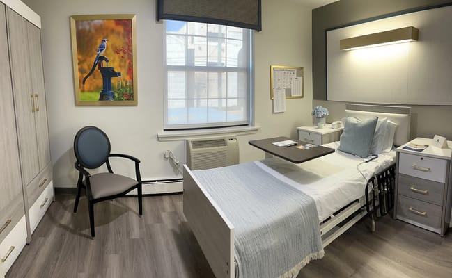 A well-furnished resident room with a bed and chair