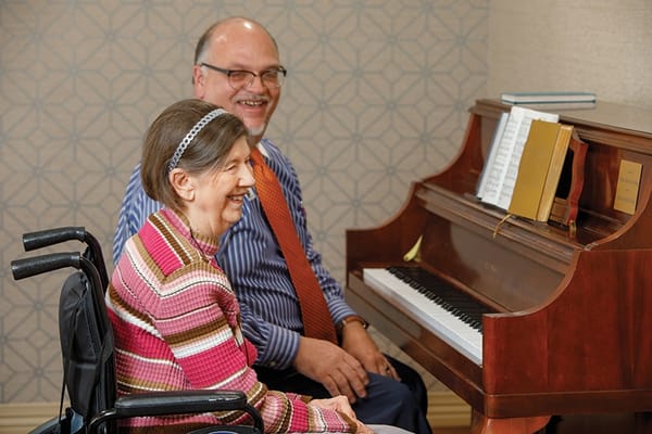 Residents enjoying music together at a piano