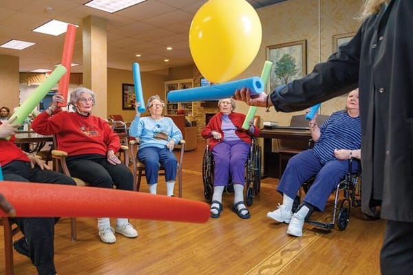 Residents engaging in a fun group activity with colorful pool noodles