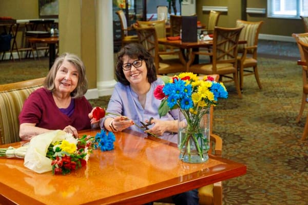 Two residents crafting with flowers in a common area