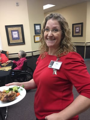 Staff member serving food to residents in the dining area