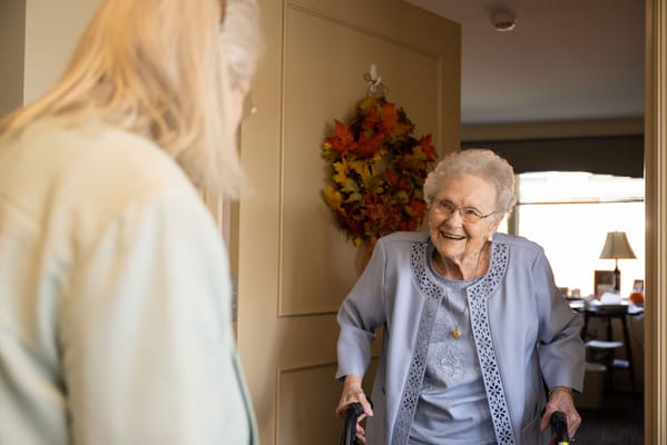A smiling resident greeting a visitor in a warm interior