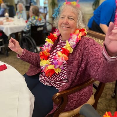 Resident enjoying a festive activity with a floral lei