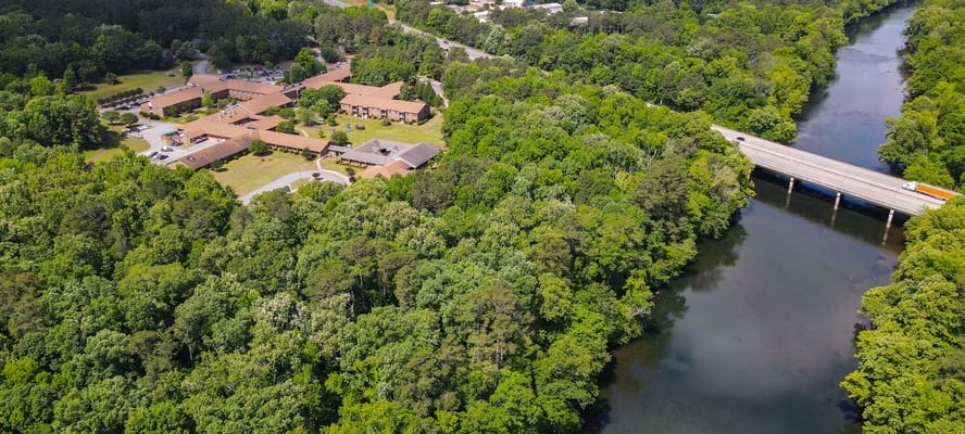 Aerial view of a senior living campus surrounded by trees and a river