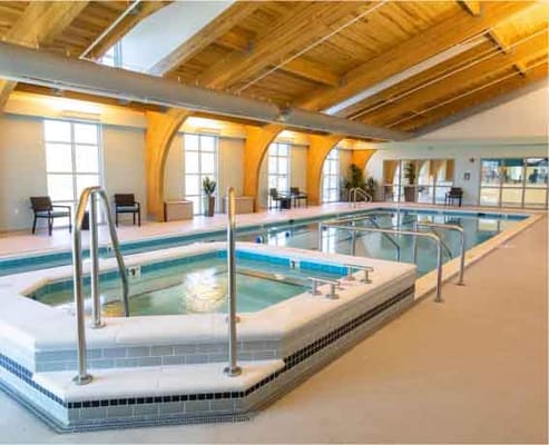 Indoor pool area with hot tub and seating