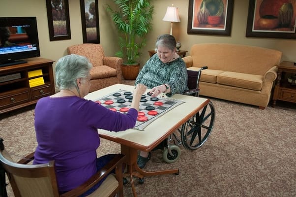 Two residents playing checkers in a common area