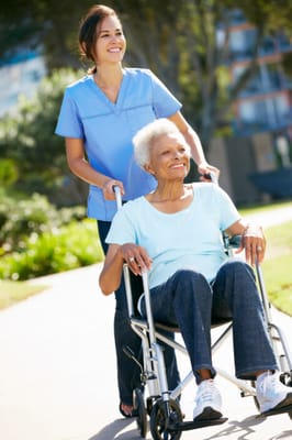 A caregiver assisting a resident in a wheelchair outdoors