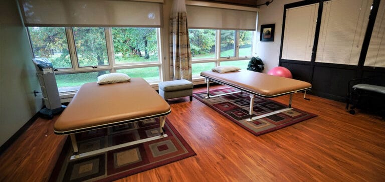 Physical therapy room with treatment tables and windows