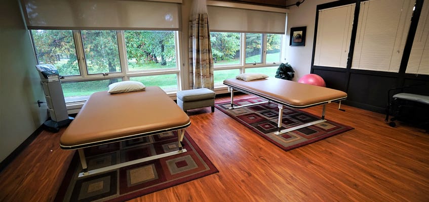 Physical therapy room with treatment tables and windows