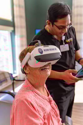 Senior resident using virtual reality headset with staff assistance