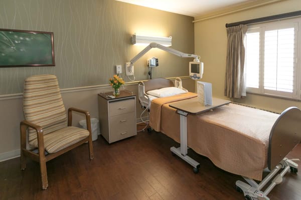 A furnished resident room with a bed and chair