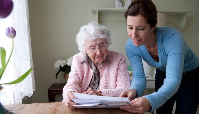 A caregiver assists an elderly woman with documents