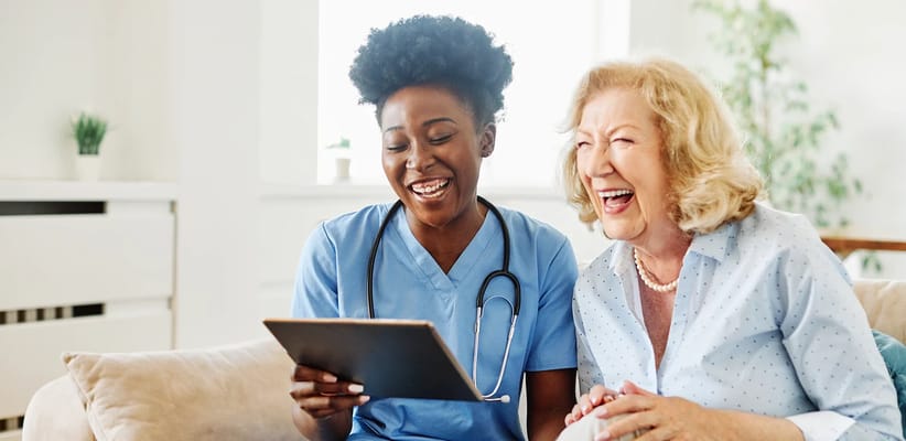 A caregiver and resident laughing together in a cozy setting