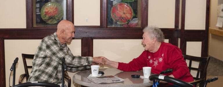 Two residents enjoying a conversation at a table in a common area