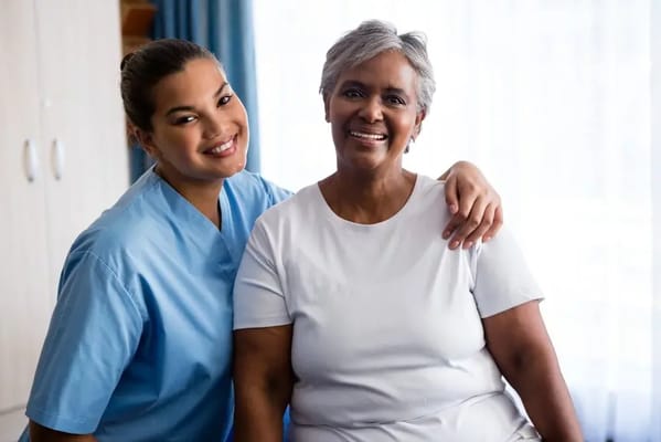 A caregiver and a resident smiling together in a room
