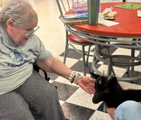 Resident interacting with a goat indoors