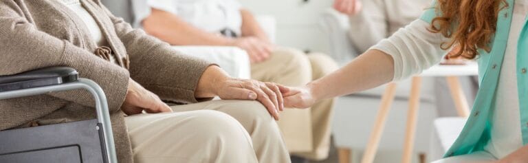 Caregiver holding a resident's hand in a common area