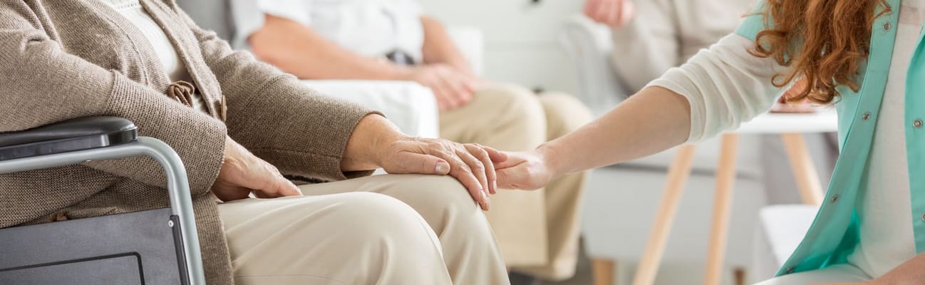 Caregiver holding a resident's hand in a common area