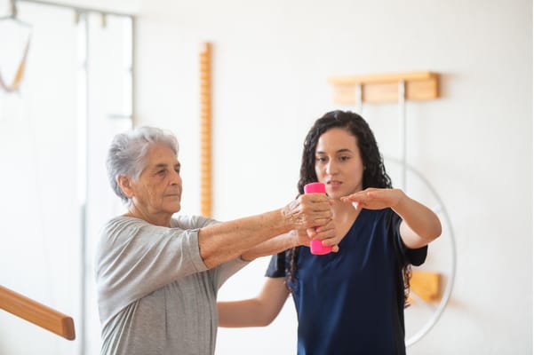 Therapist assisting a senior with light weights in a rehabilitation session
